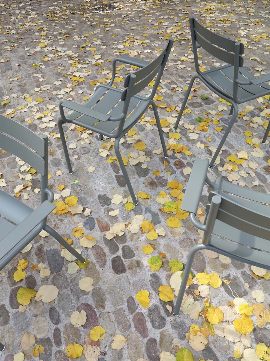 Fermob «Luxembourg» Gartenstühle mit Armlehnen auf Kopfsteinpflaster mit gelben Gingko-Blättern im Herbst