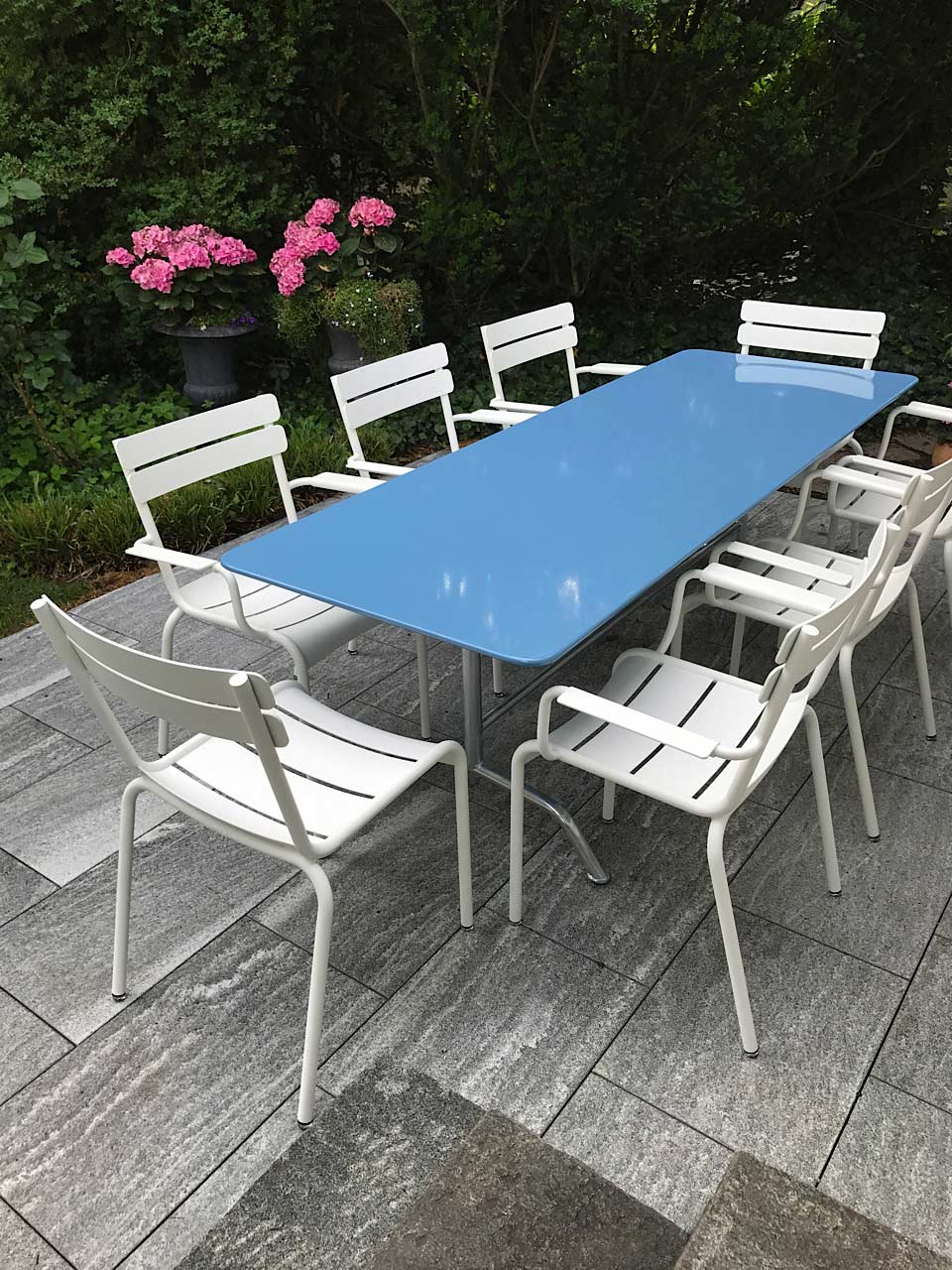 Langer blauer Bättig Gartentisch mit weissen Luxembourg Gartenstühlen mit und ohne Armlehnen