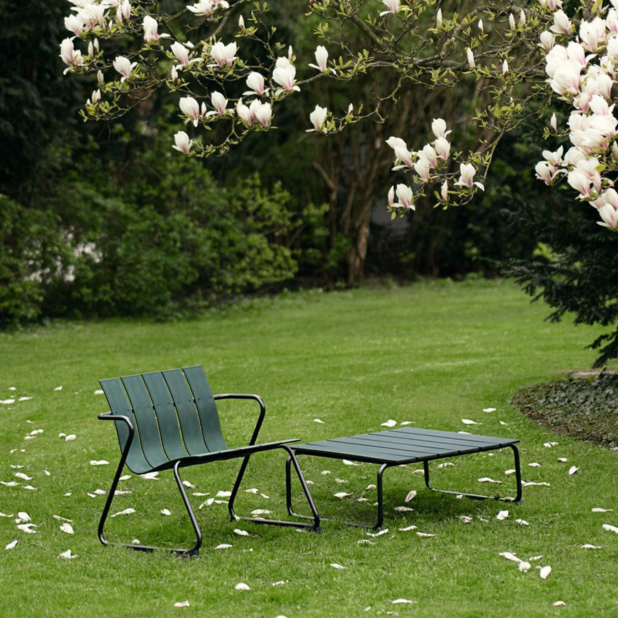 Ocean Lounge Chair und Lounge Table in Grün unter blühendem Magnolienbaum auf saftig grünem Rasen